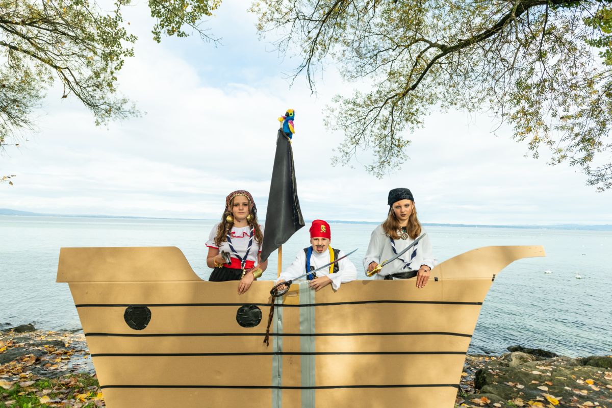 Kinder als Piraten in einem Kartonschiff am Ufer