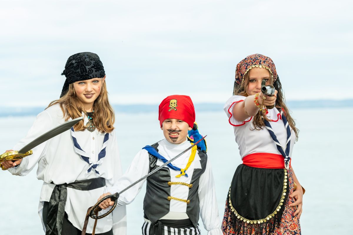 Drei Kinder als Piraten verkleidet am Seeufer