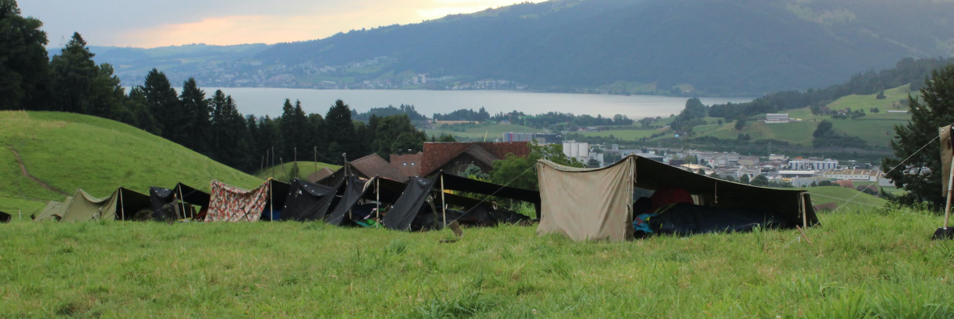 Zeltlager auf einer Wiese über dem See